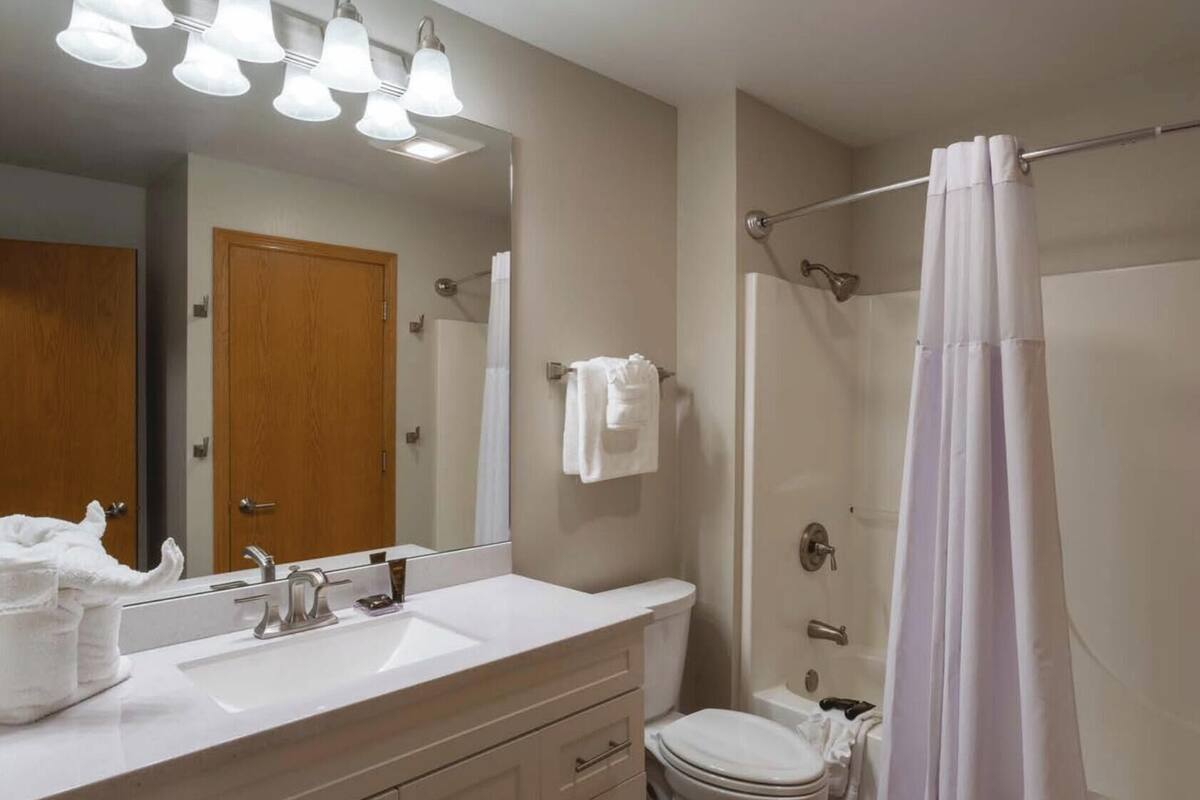 A bathroom with a sink, mirror, and shower.