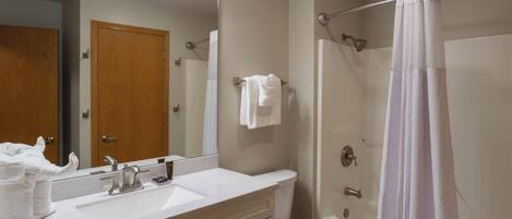 A bathroom with a sink, mirror, and shower.