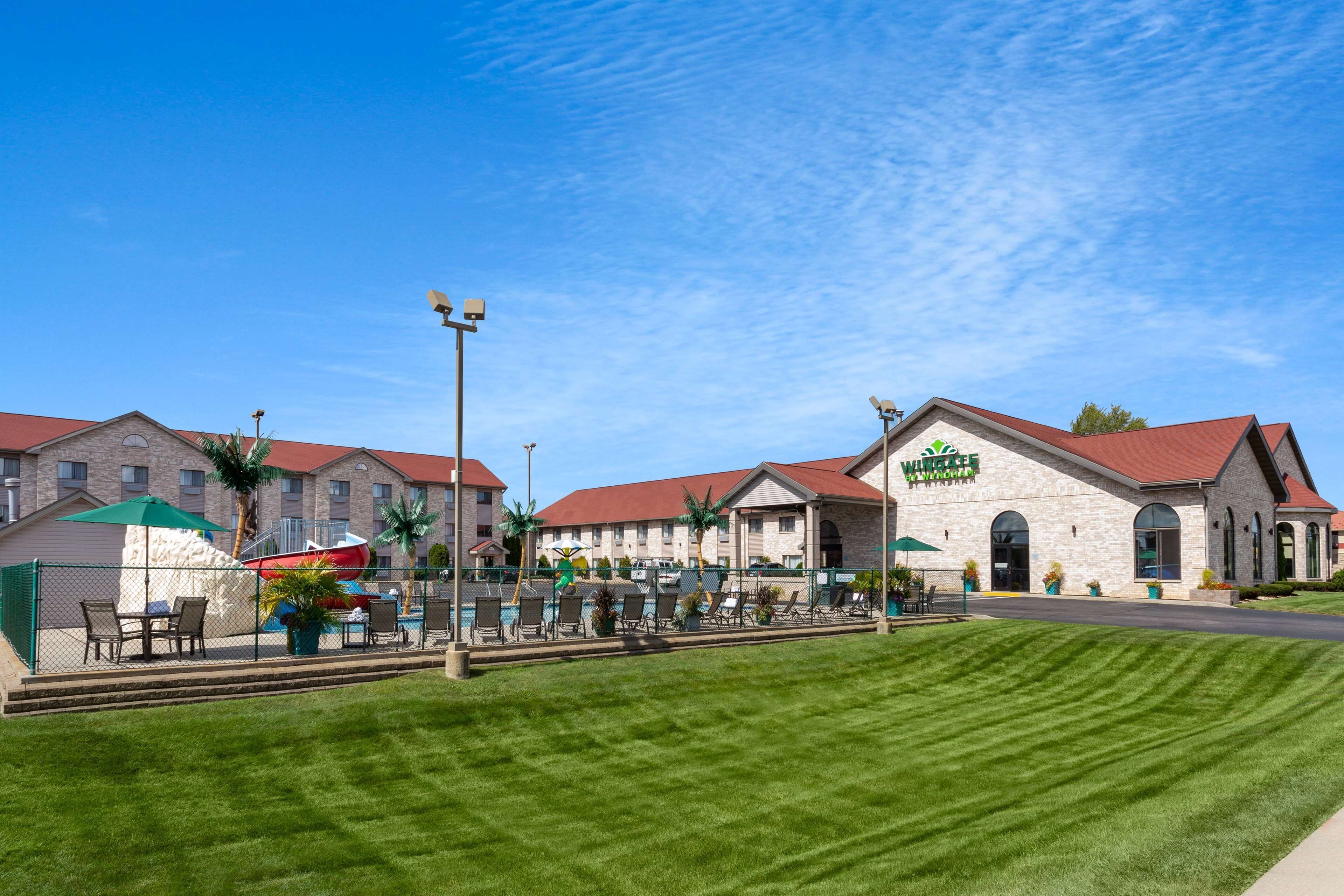 A hotel with a pool area, outdoor seating, and a well-maintained lawn.