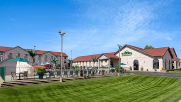 A hotel with a pool area, outdoor seating, and a well-maintained lawn.