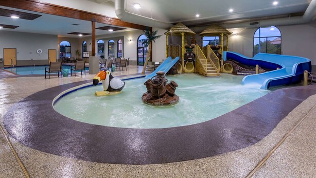 An indoor pool area with a slide, a play structure, and a hot tub. - Wingate by Wyndham Wisconsin Dells Waterpark (Baraboo)