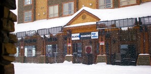 Un edificio de ladrillo con techo cubierto de nieve y un letrero que dice 'Black Diamond Bar & Grill'.