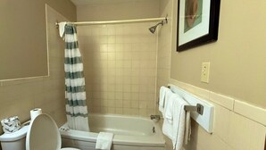 Une salle de bain équipée de toilettes, d’une baignoire, d’une douche et d’un porte-serviettes.
