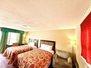 A hotel room with two beds, a chair, a desk, and a window with curtains. - Mohawk Motel (Brantford)