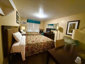 A hotel room with two beds, a desk, a TV, a mirror, and a window with curtains. - Mohawk Motel (Brantford)