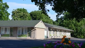Un motel avec une série de chambres, un parking couvert et un jardin fleuri.