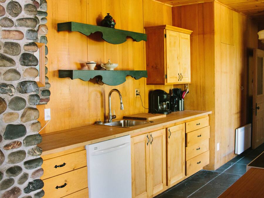 Una cocina con armarios de madera, una pared de piedra y un lavavajillas.