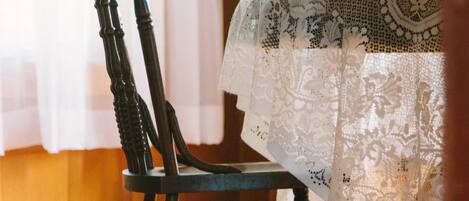 A dining table with a lace tablecloth and a wooden chair with a curved backrest.
