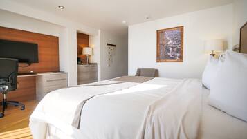 Una habitación de hotel con una cama, un escritorio, un televisor y un cuadro en la pared.