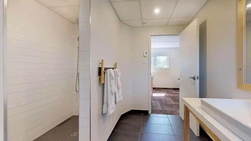 Une salle de bain moderne avec une douche, un lavabo et un miroir.