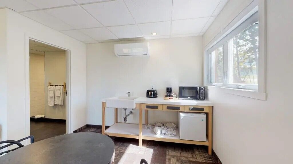A compact kitchen with a sink, microwave, and small refrigerator.