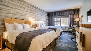 A hotel room with two beds, a desk, a chair, a window with curtains, and a marble wall. - Manoir Belle Plage (Carleton-sur-Mer)