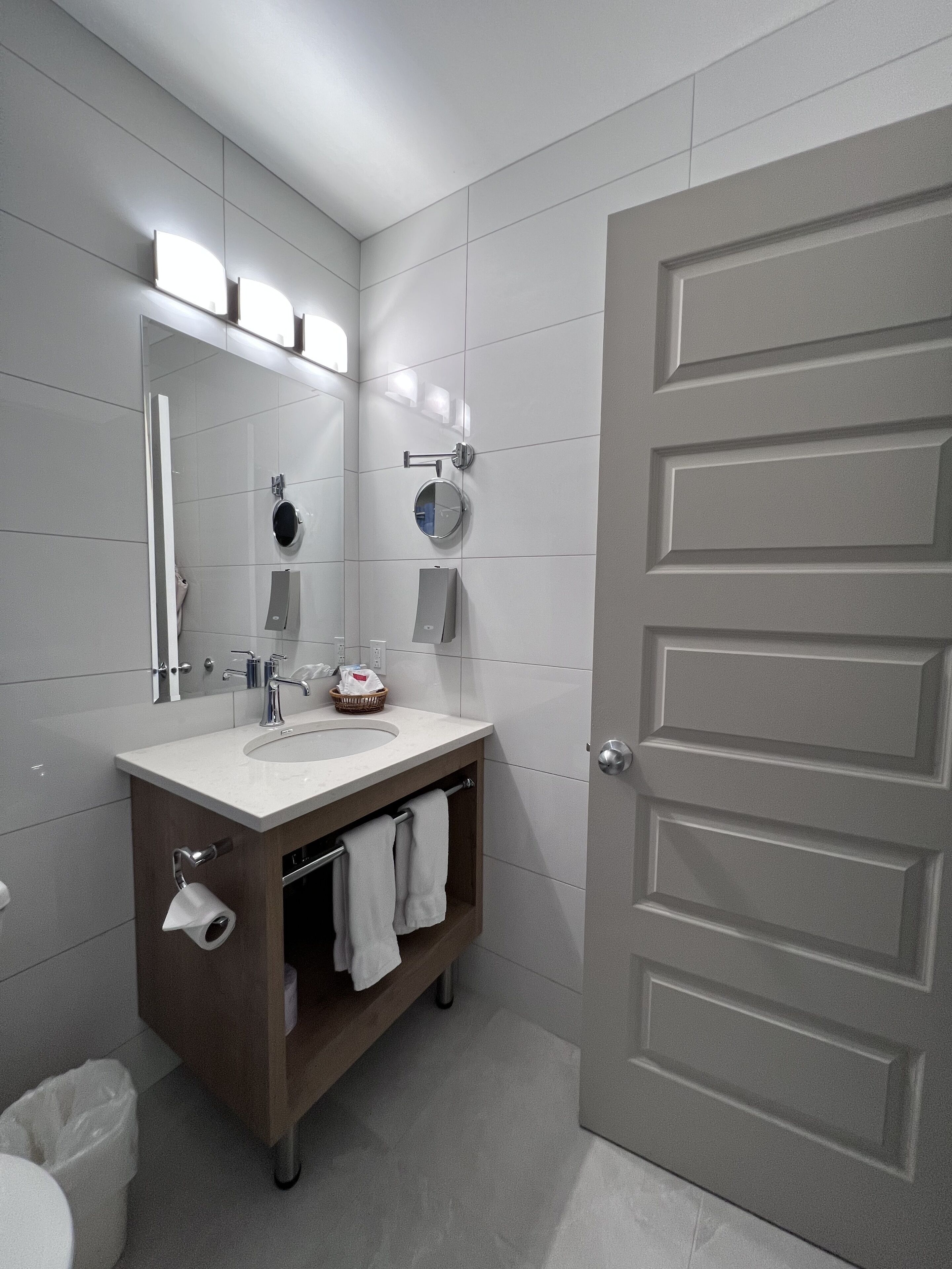 Une salle de bain moderne avec un lavabo blanc, un miroir et un porte-serviettes.