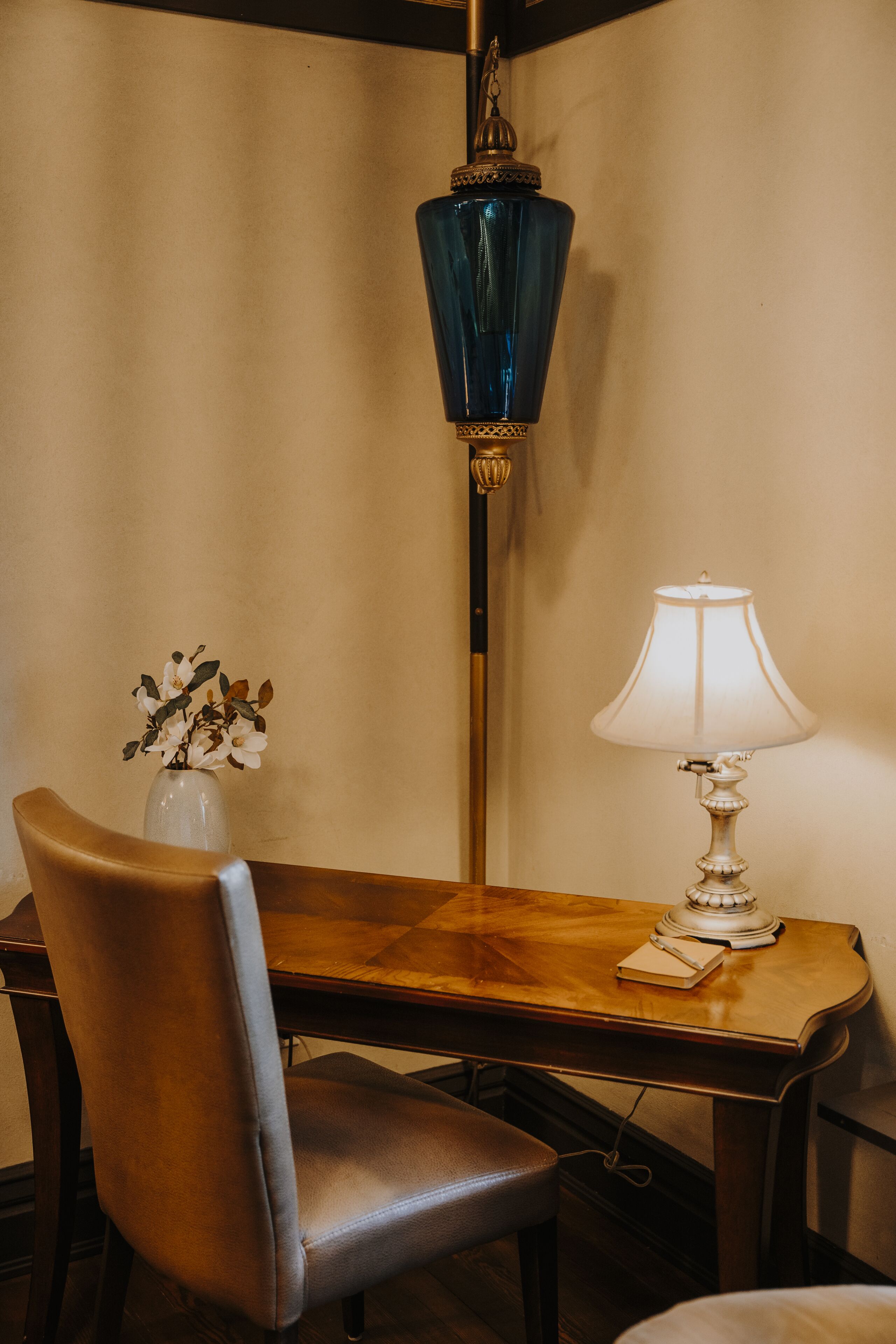 Een houten tafel met een witte lamp en een vaas vol bloemen.