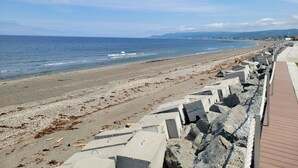 A beach with a wooden walkway and concrete barriers. - Manoir sur Mer (Sainte-Anne-des-Monts)