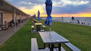 A seaside promenade with picnic tables and umbrellas, overlooking the ocean. - Manoir sur Mer (Sainte-Anne-des-Monts)