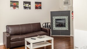Una sala de estar con un sofá de cuero marrón, una mesa de centro blanca y una chimenea con revestimiento de azulejos.