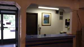 A reception desk with a framed picture on the wall, a closed door, and a window with a 'CLOSED' sign. - Royal City Motor Inn (Brooks)