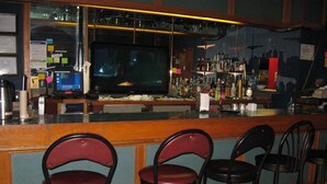 A bar area with a counter, stools, and a television. - Royal City Motor Inn (Brooks)