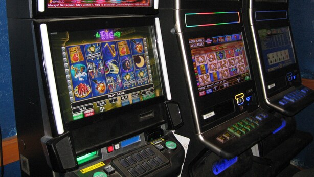 A row of slot machines with various game screens and buttons. - Royal City Motor Inn (Brooks)