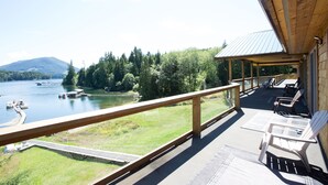 A wooden deck with a view of a lake and forest. - Kagoagh Resort and Fishing Lodge (Quatsino)