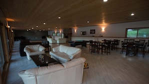 A spacious living area with a pool table, leather sofas, and a dining area with wooden tables and chairs. - Kagoagh Resort and Fishing Lodge (Quatsino)
