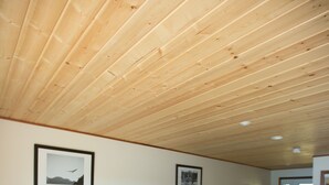 A hotel room with two beds, wooden ceiling, framed pictures on the wall, and a door leading outside. - Kagoagh Resort and Fishing Lodge (Quatsino)