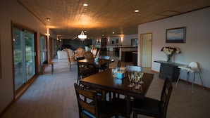 A spacious dining area with a wooden ceiling, large windows, and a view of the outdoors. - Kagoagh Resort and Fishing Lodge (Quatsino)