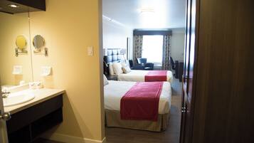 Une chambre d’hôtel avec salle de bain, deux lits, un bureau et une chaise.