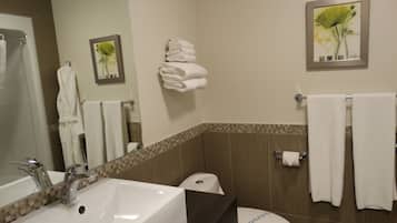 A bathroom with a sink, mirror, toilet, and towels.