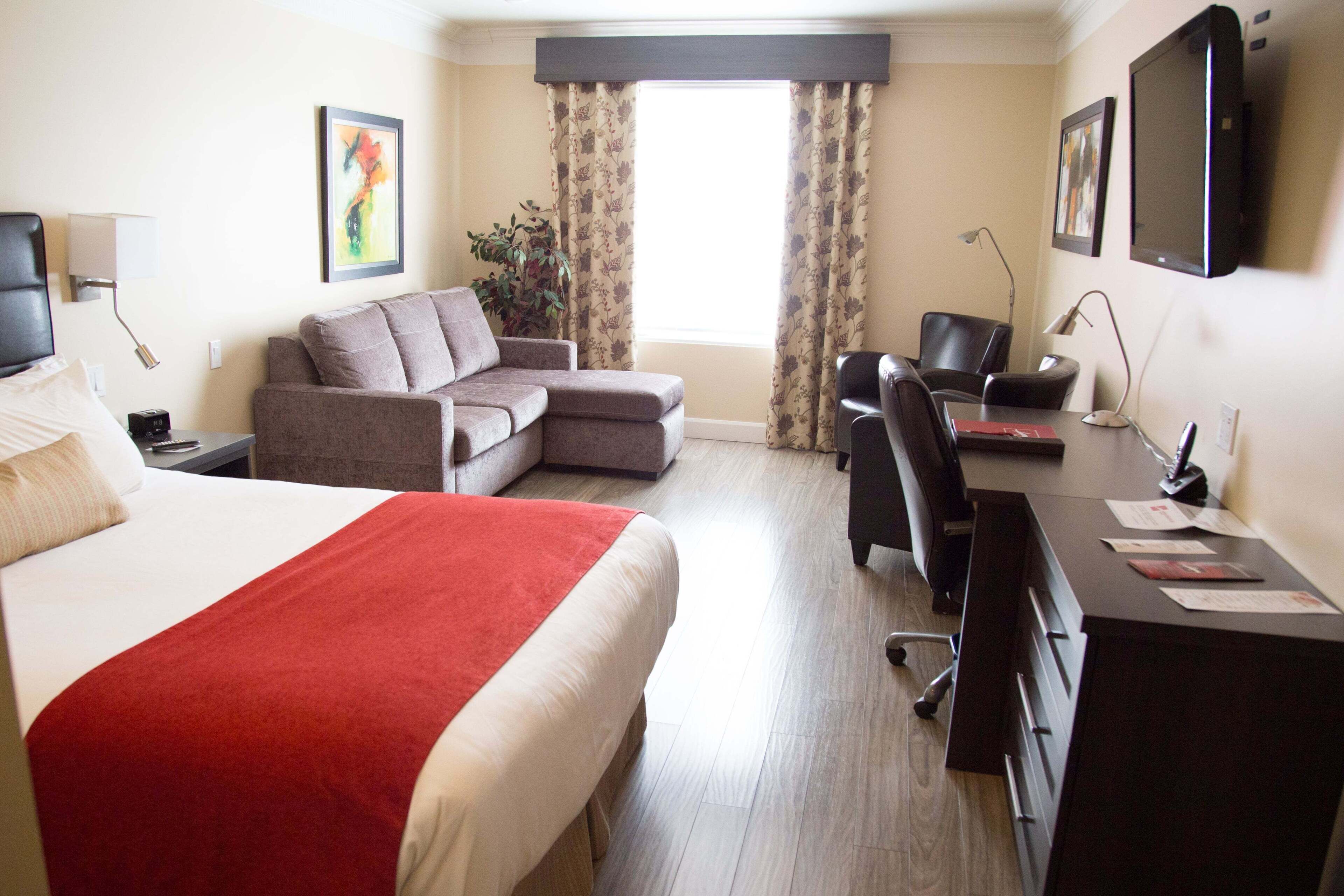 Una habitación de hotel con cama, sofá, escritorio y televisión.