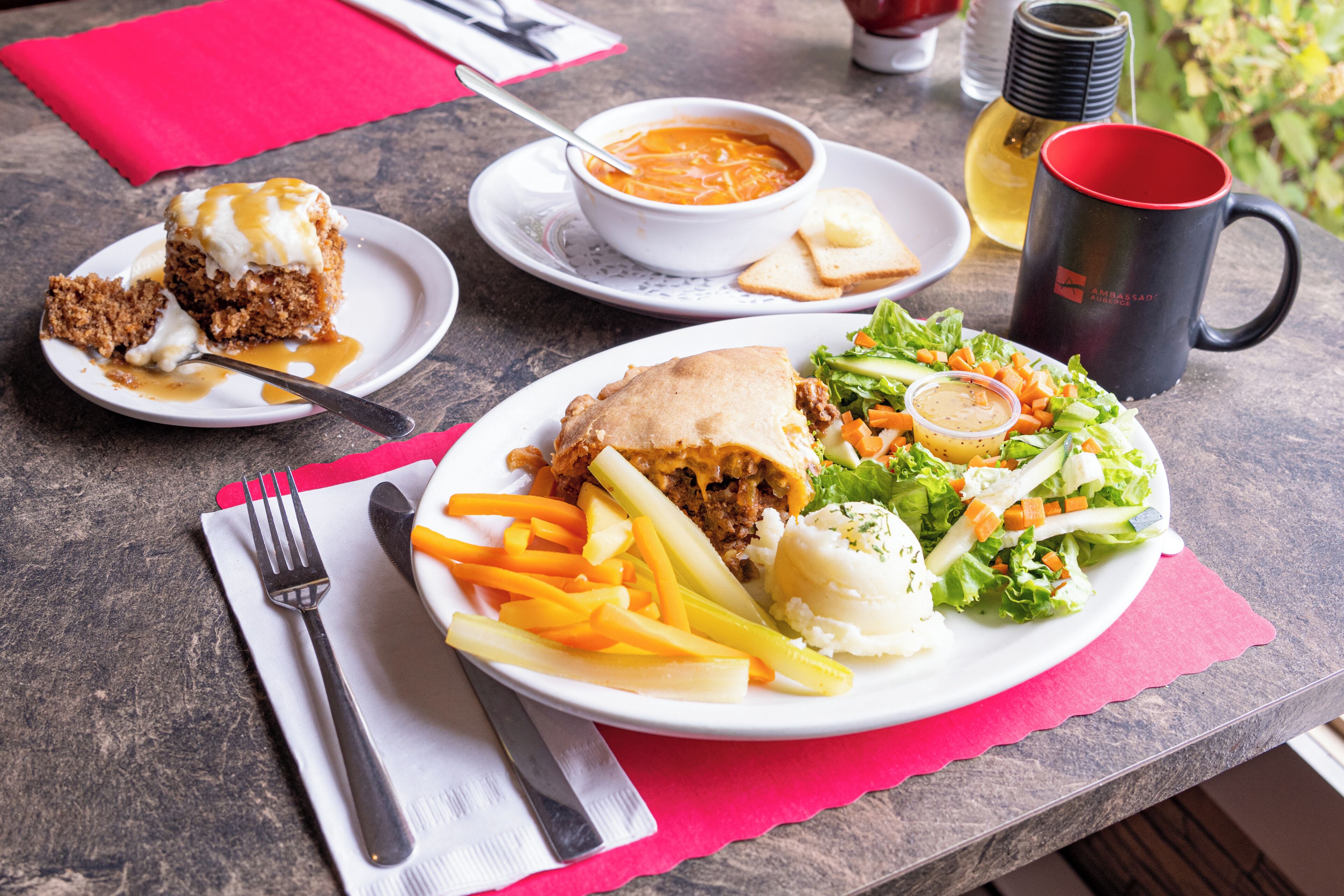 Eine Mahlzeit mit Sandwich, Pommes, Salat und Suppe auf einem Tisch.