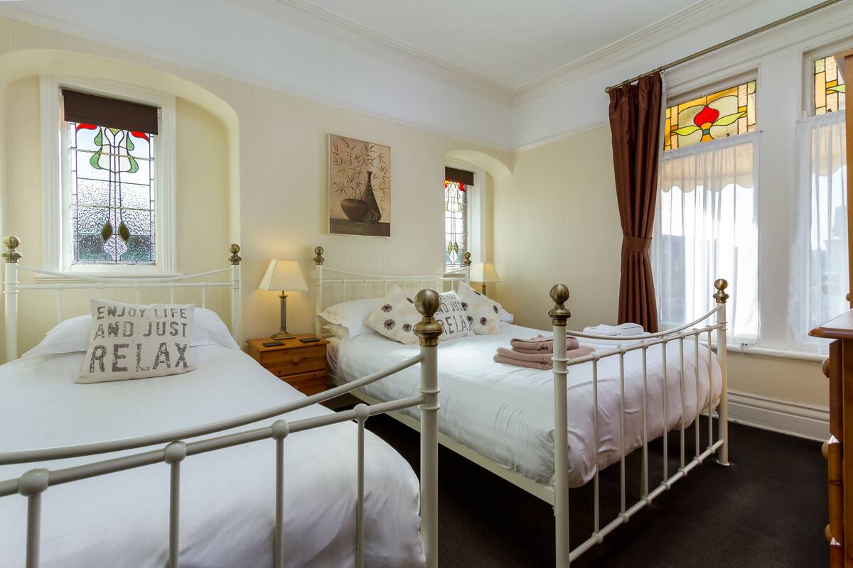 Un dormitorio con dos camas, un cuadro en la pared y una ventana con cortinas.
