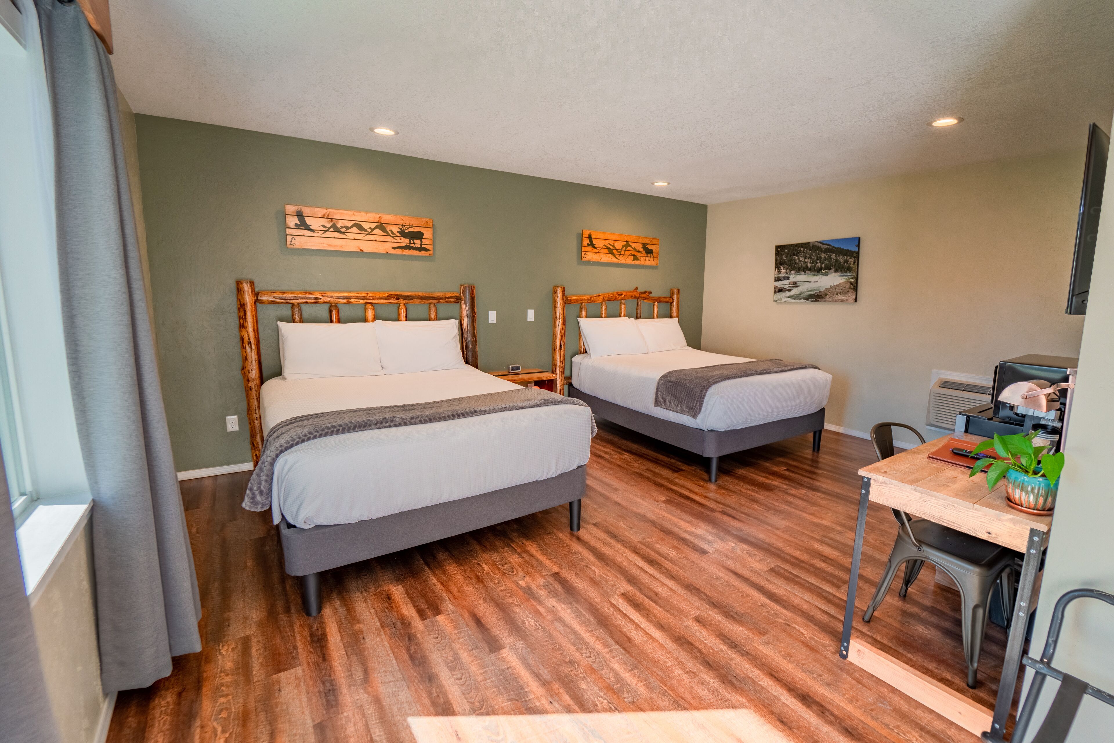 A room with two wooden beds, a desk, and a chair.