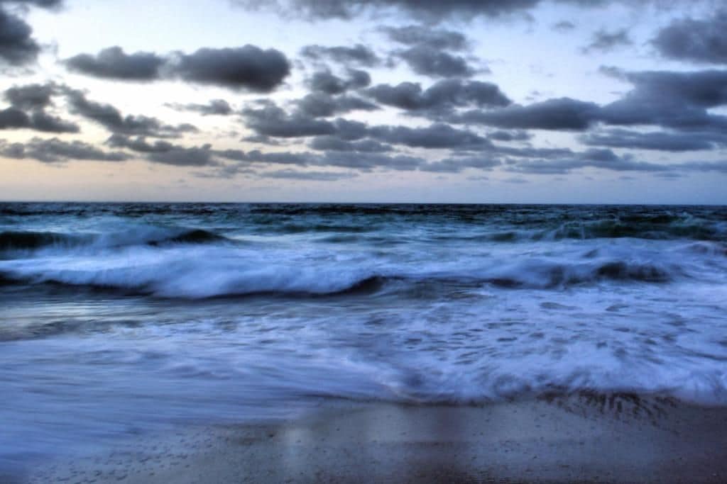 A beach with waves and a cloudy sky.
