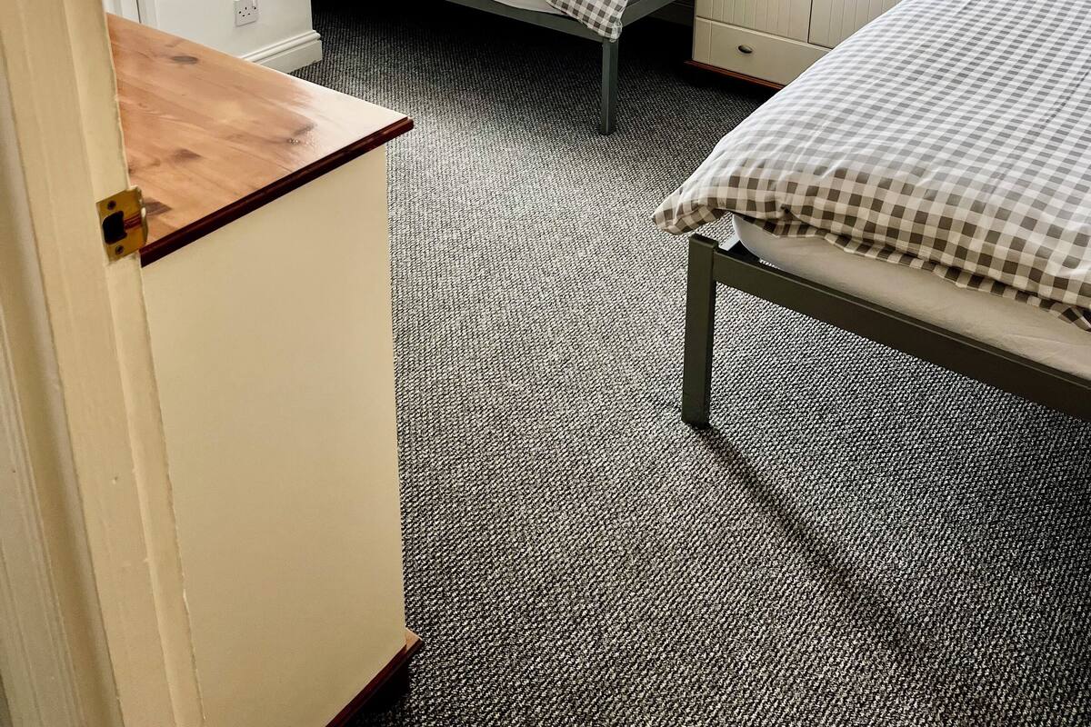 A bedroom with two single beds, a wardrobe, a mirror, and a small desk.