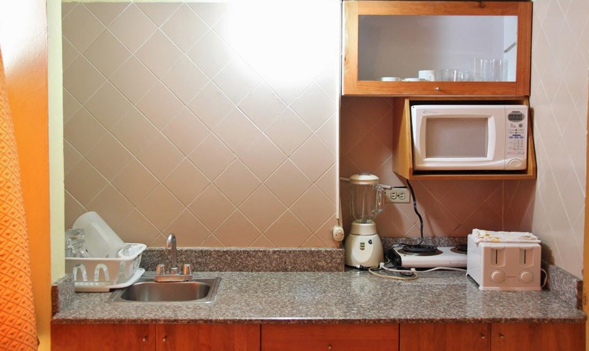 Una cocina con encimera de granito, un fregadero, un microondas, un tostador y una licuadora.