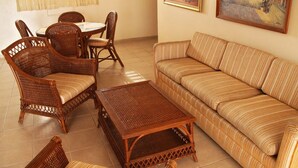 A living room with wicker furniture, a striped sofa, and a coffee table. - Aparta Hotel Turey (Santo Domingo)