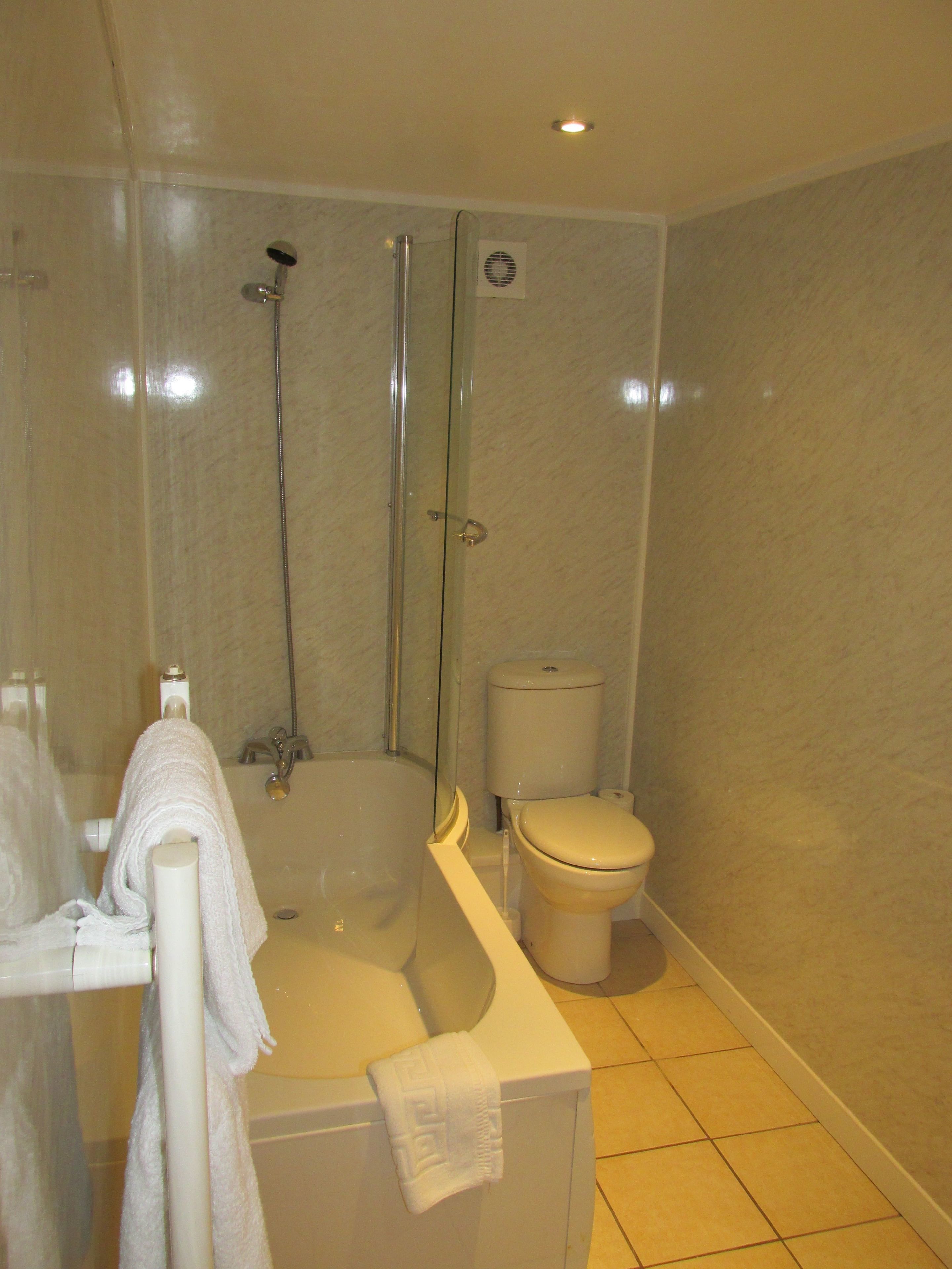 A bathroom with a bathtub, a toilet, and a glass-enclosed shower area.