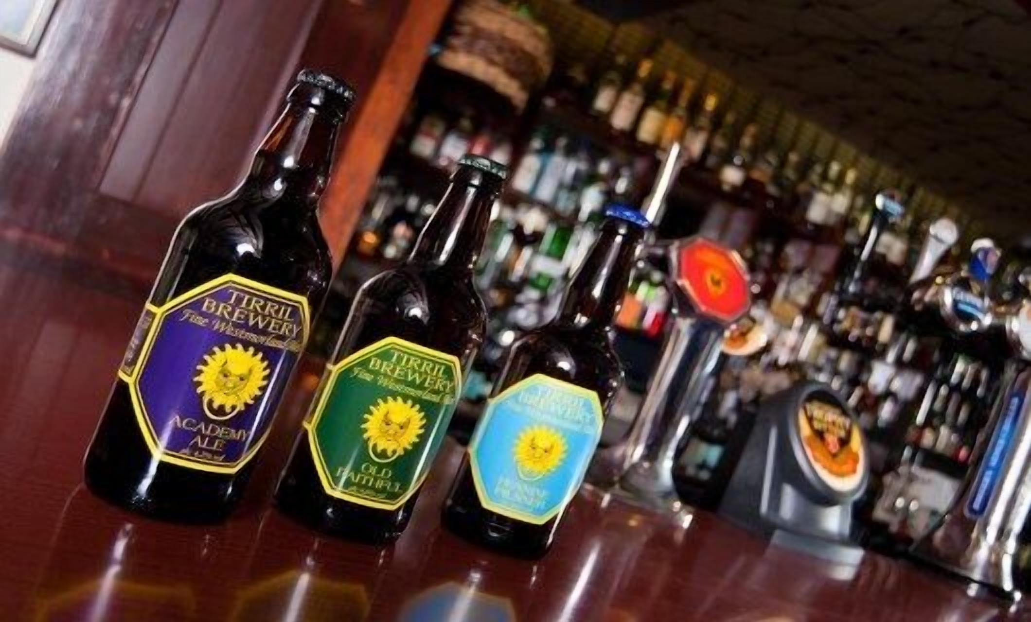 Three bottles of beer with labels on a bar counter.