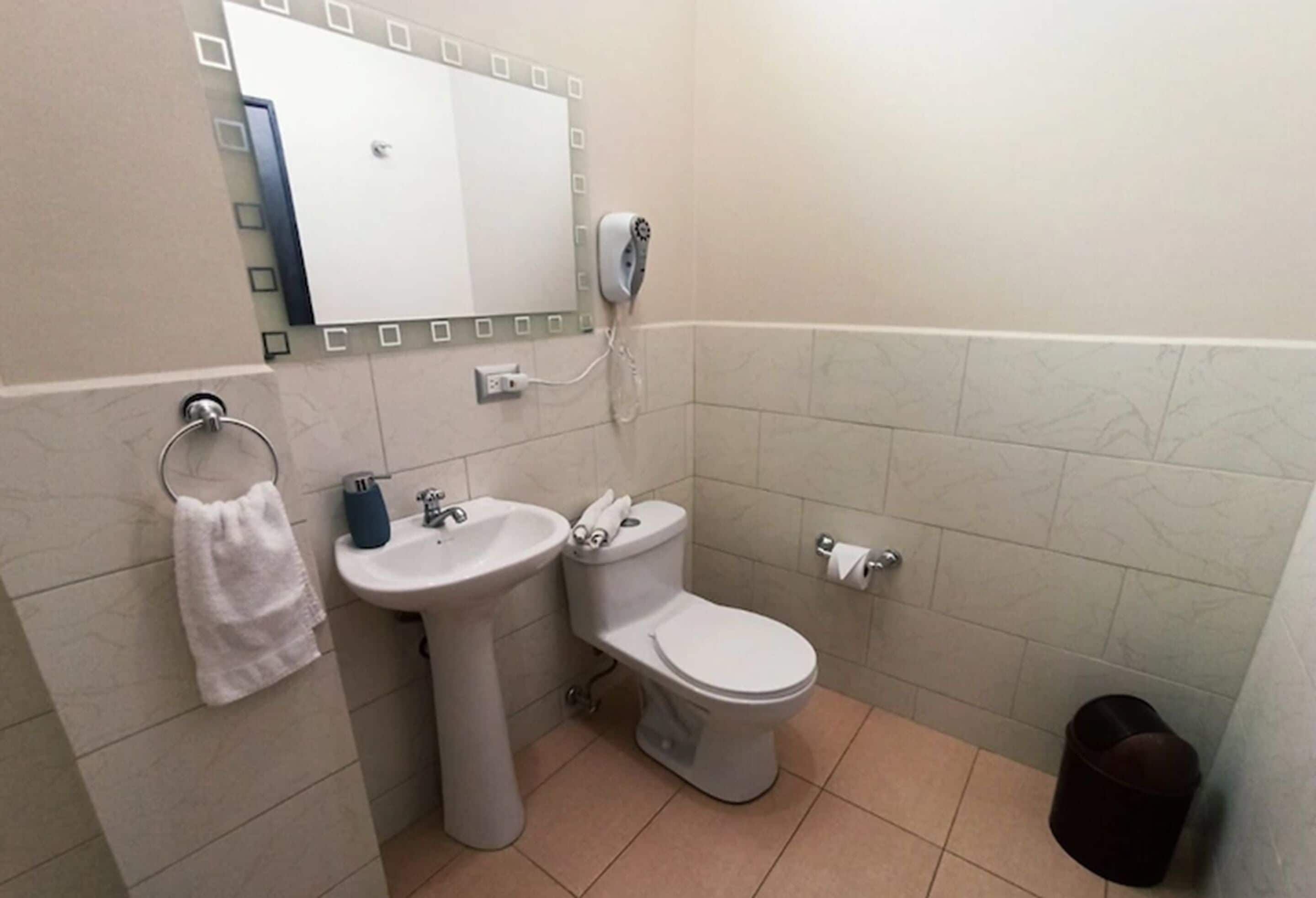 A bathroom with a sink, toilet, and a towel rack.