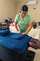 Une pièce équipée d’une table de massage, d’un fauteuil de massage et d’une étagère contenant divers objets.