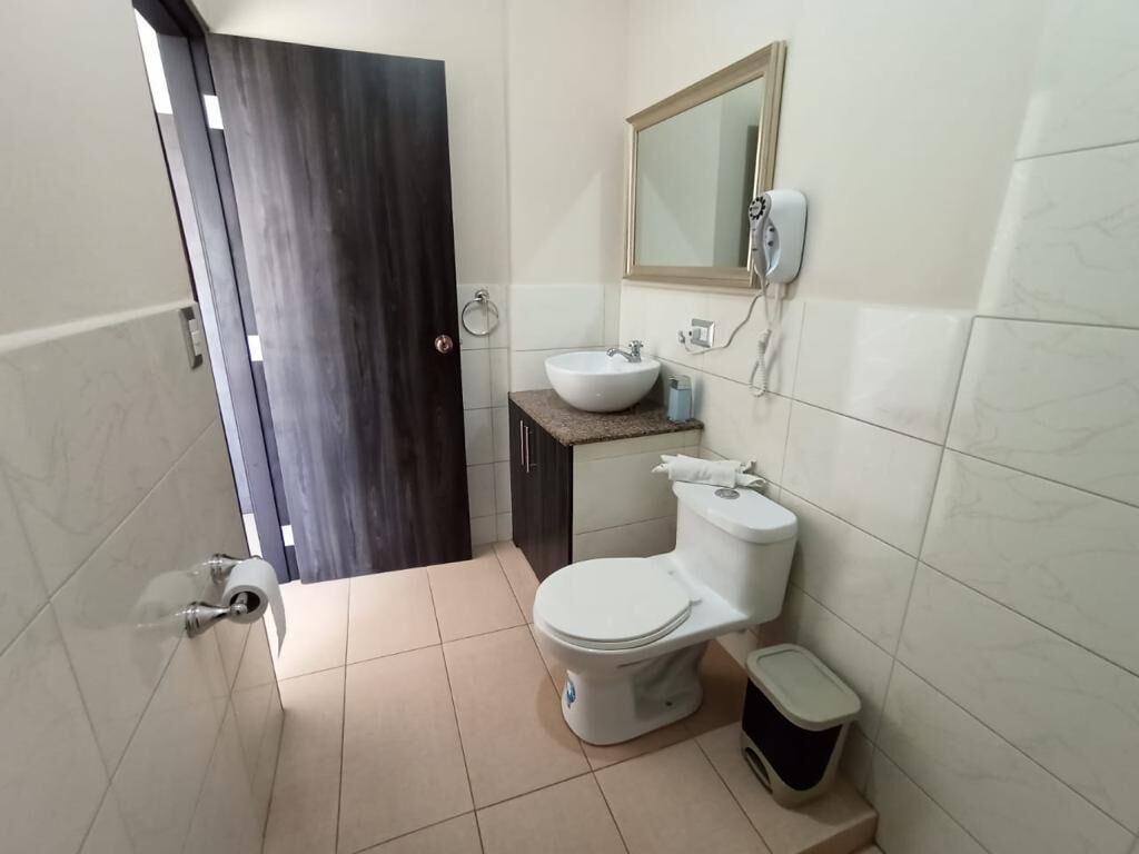 A bathroom with a toilet, sink, and mirror.