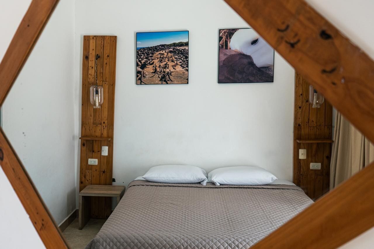 Un dormitorio con una cama, dos lámparas de pared y dos cuadros enmarcados.