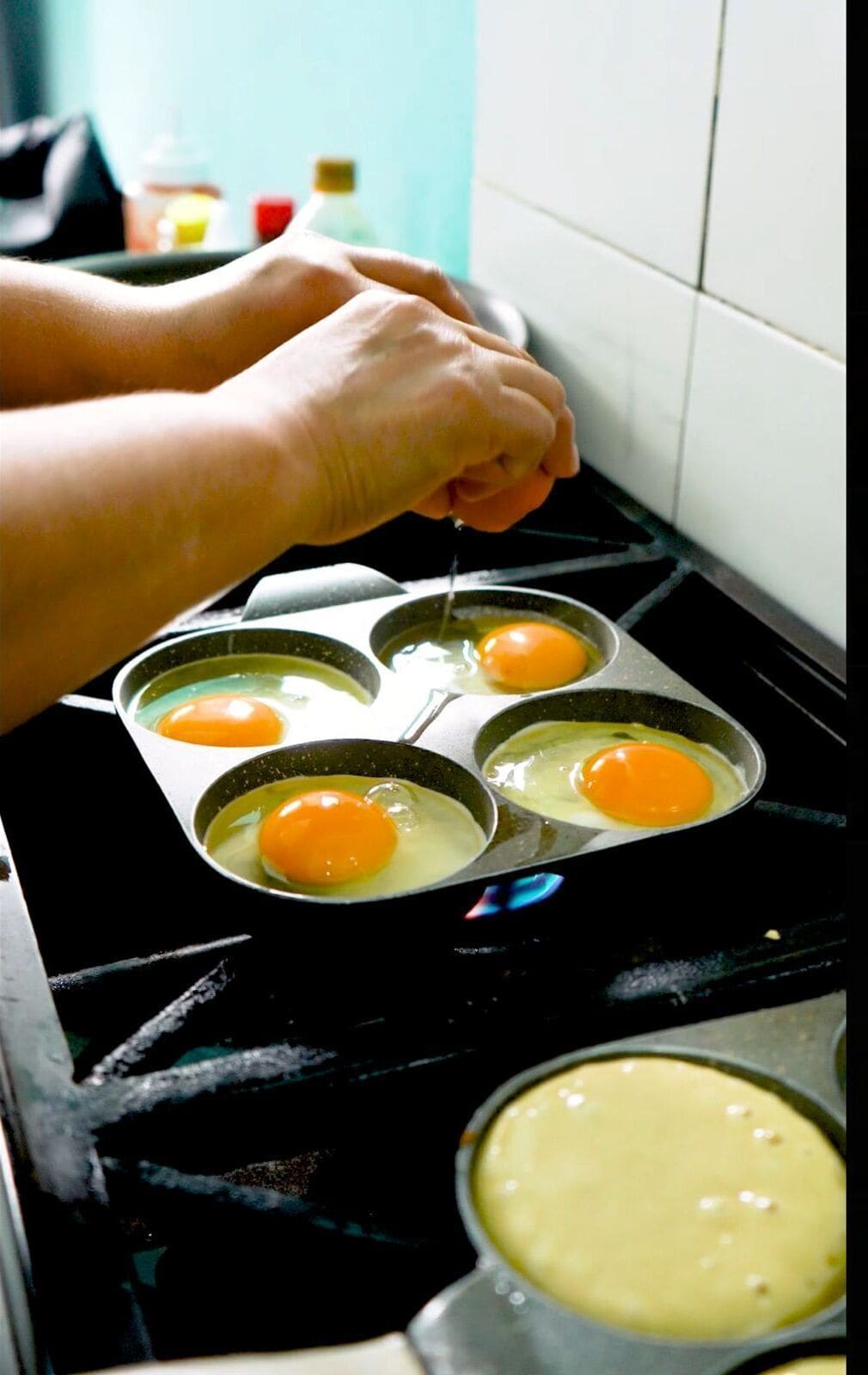Una persona cocinando huevos en una sartén sobre la hornilla.