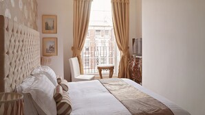 Habitación de hotel con una cama grande, una silla, una mesita y un televisor.