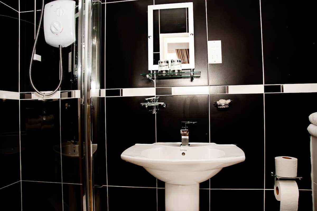 A bathroom with a white sink, a glass shower enclosure, and a mirror above the sink.