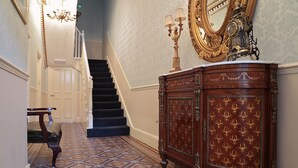 Una imponente escalera con un suelo de diseño, una silla de madera y un aparador de madera con detalles ornamentales.