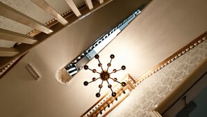 Una imponente escalera con candelabro y techo decorativo.