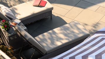 Una piscina al aire libre, sombrillas, sillones reclinables de piscina